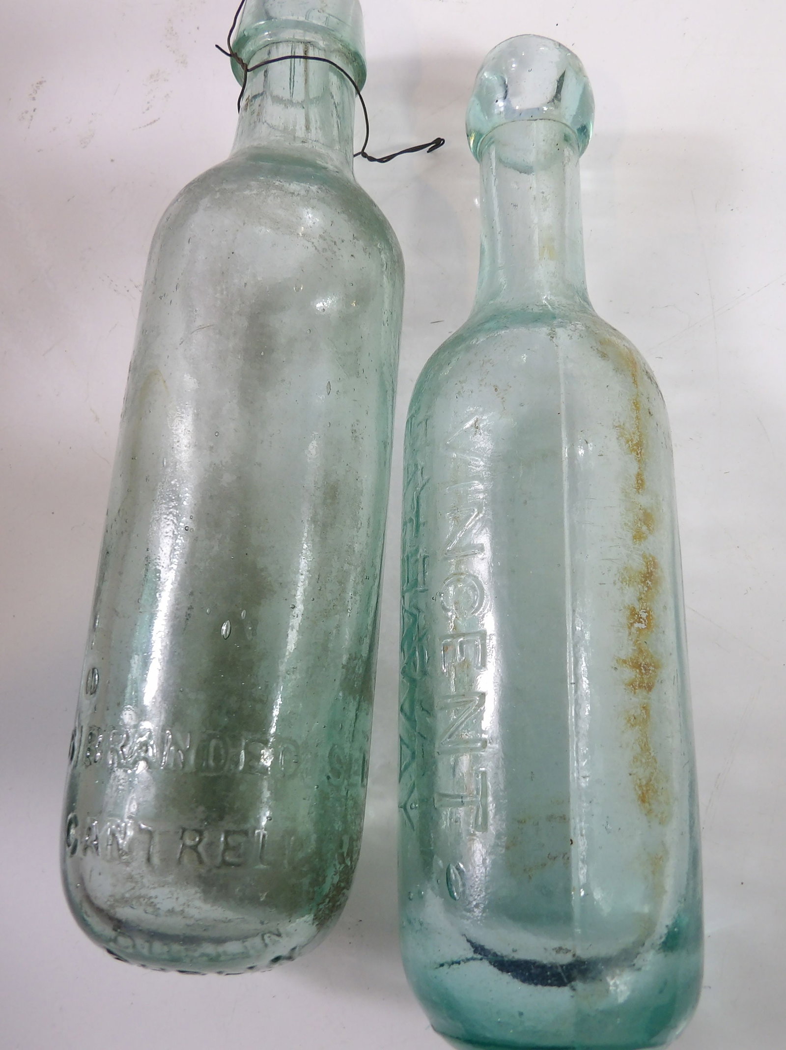 Pair of Vintage Embossed Glass Soda Bottles: Pair of Vintage Embossed Glass Soda Bottles, Round Bottoms. All measurements approximate. Please see photos for condition and details. Selling as is from 04281.