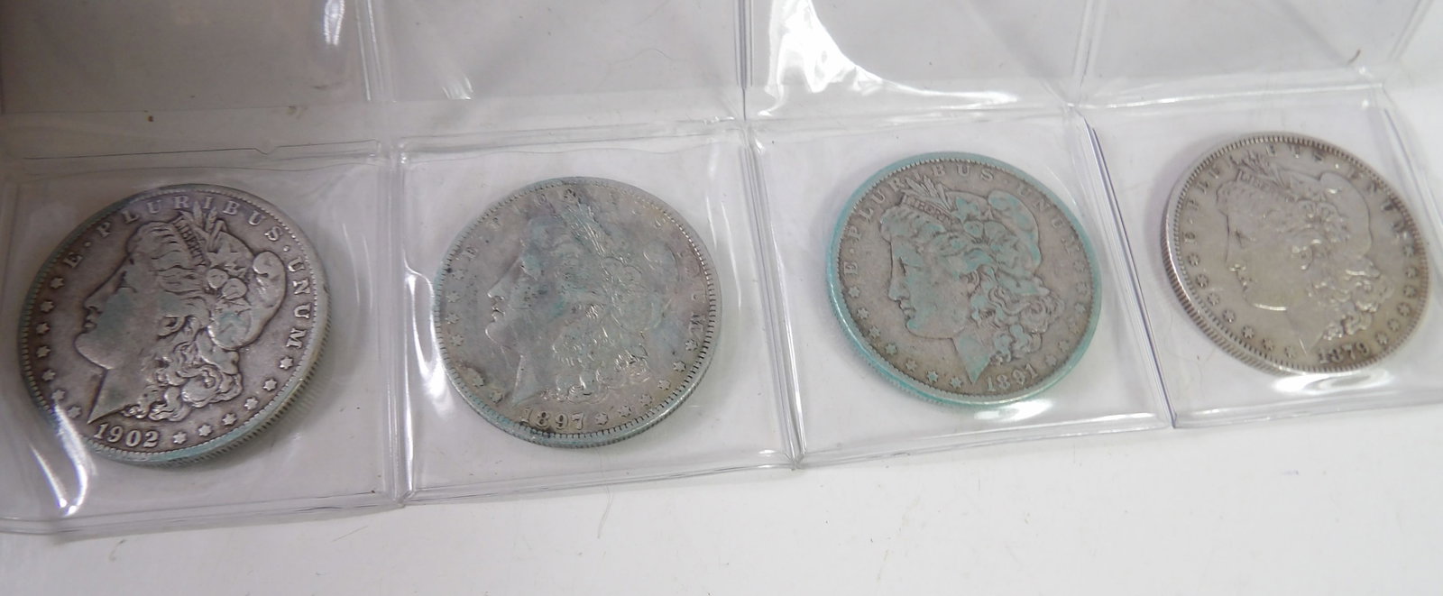 1879, 1891, 1897, & 1902 Morgan Dollars: Lot of 4 Morgan Dollars. 1879, 1891, 1897, and 1902. All measurements approximate. Please see photos for condition and details. Selling as is from 04281.