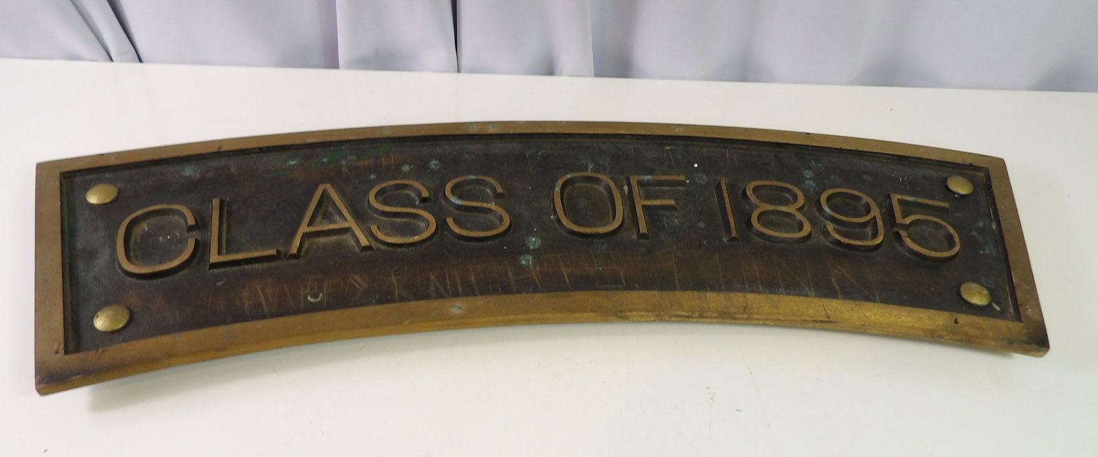 Vintage Brass Curved Sign, Class of 1895: Vintage Solid Brass Curved Sign. Class of 1895. 8" X 30" Has a Few Scratches. (Looks like kids tried to carve names on it.) Hardly Noticeable. All measurements approximate. Please see photos for condi