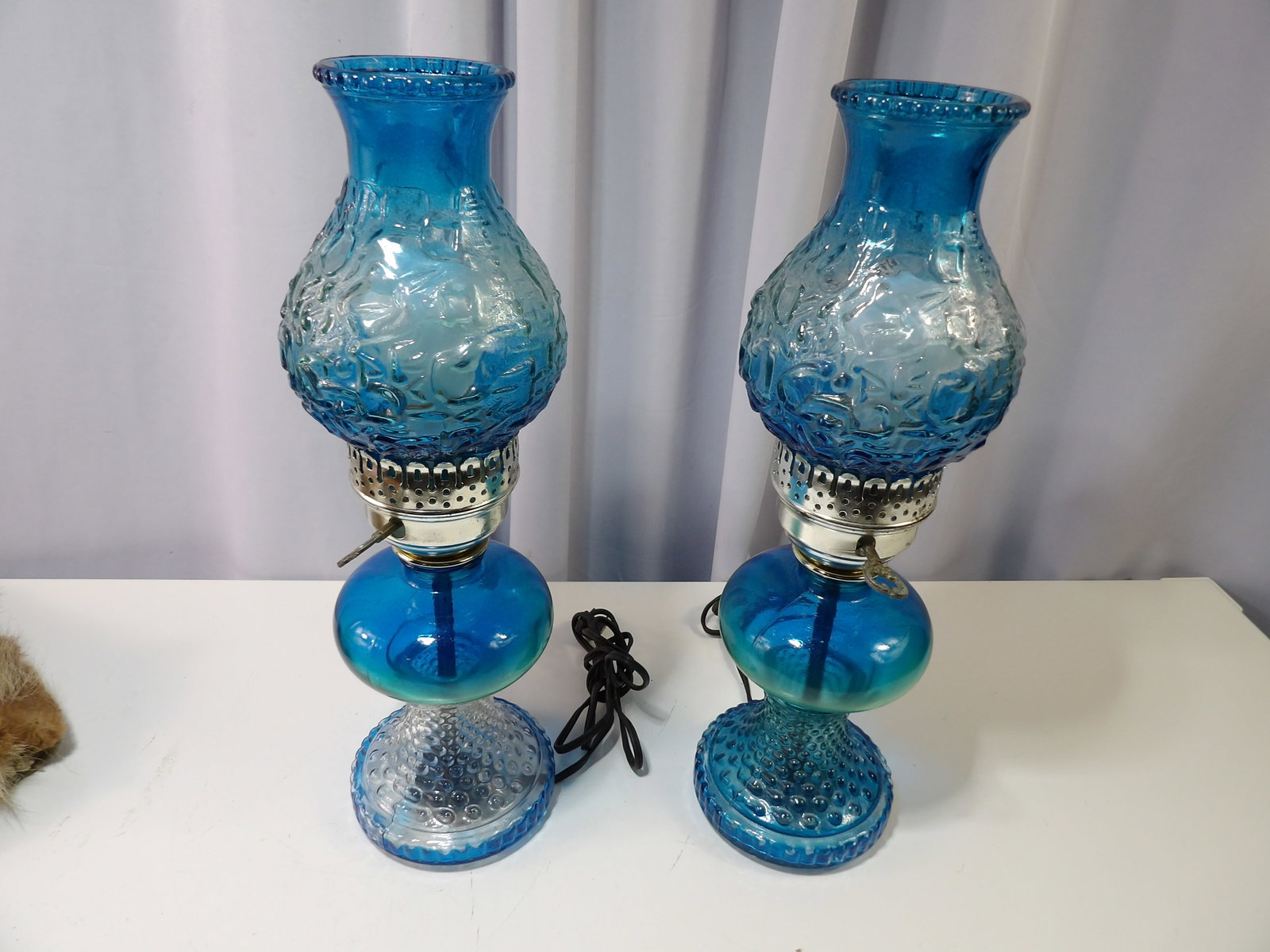 Pair of Blue Hobnail Glass Hurricane Lamps: Pair of Vintage Blue Hobnail Glass Hurricane Lamps with Embossed Design. All measurements approximate. Please see photos for condition and details. Selling as is from 04281.