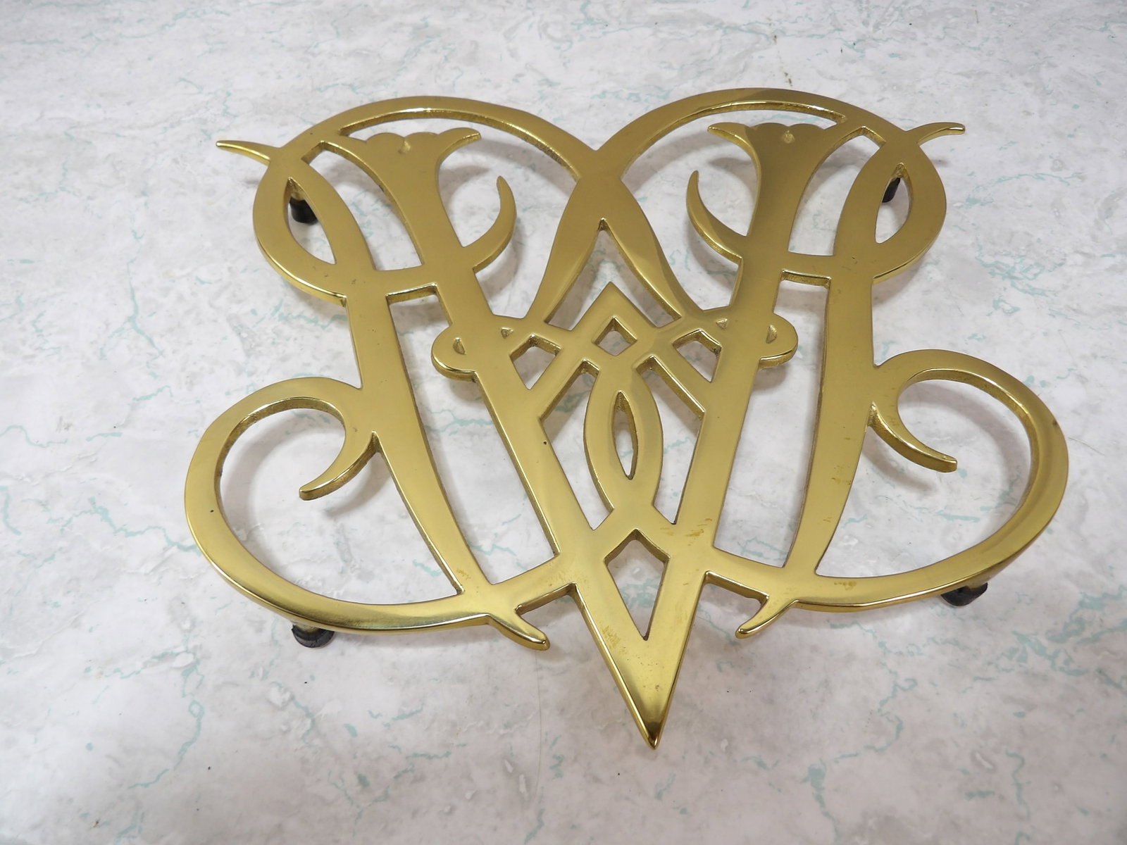 Williamsburg Queen Anne Cypher Brass Trivet: Vintage Williamsburg Queen Anne Cypher Brass Trivet. 5" Across. All measurements approximate. Please see photos for condition and details. Selling as is from 04281.