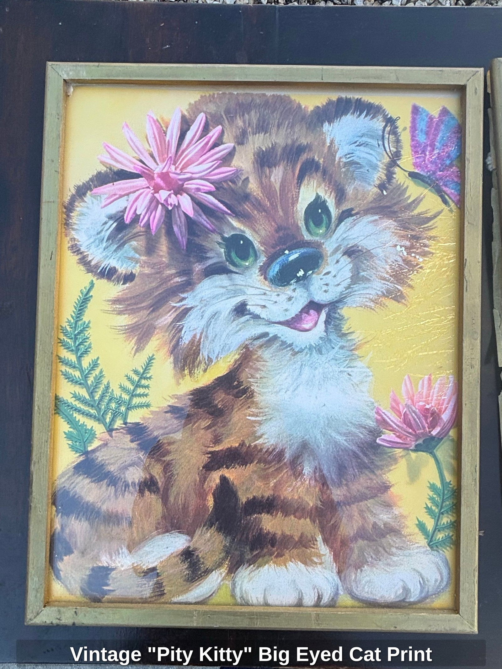 Vintage "Pity Kitty" Big Eyed Cat Print: This vintage framed art print features a "Pity Kitty" with large, expressive green eyes, adorned with flowers and a butterfly. The artwork is rendered in a soft, illustrative style with a palette of