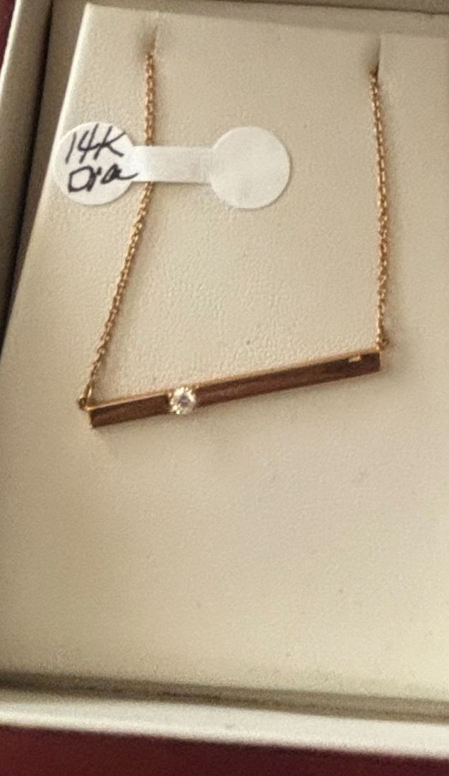 14k Gold Bar Necklace with Diamond Accent: This elegant necklace features a horizontal bar pendant crafted from 14k gold, likely rose gold given the hue. A single, small diamond is centrally set into the bar, adding a subtle sparkle. The
