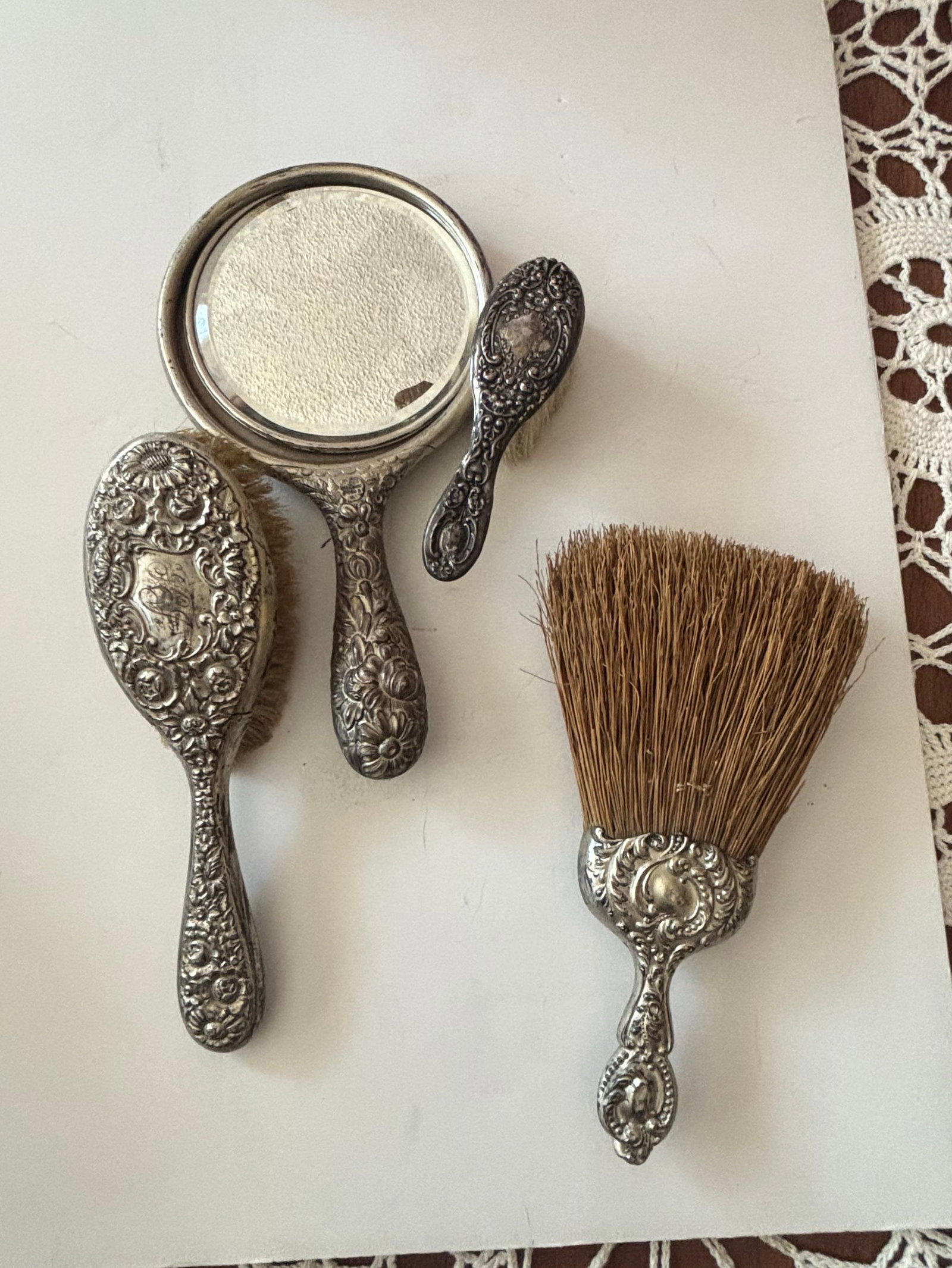 Victorian Sterling Silver Vanity Set with Floral Repoussé and Crest: This oil on canvas painting depicts a seated figure with a pensive expression, rendered in a somewhat stylized manner. The figure has fair skin, with a shock of reddish hair and is dressed in a white