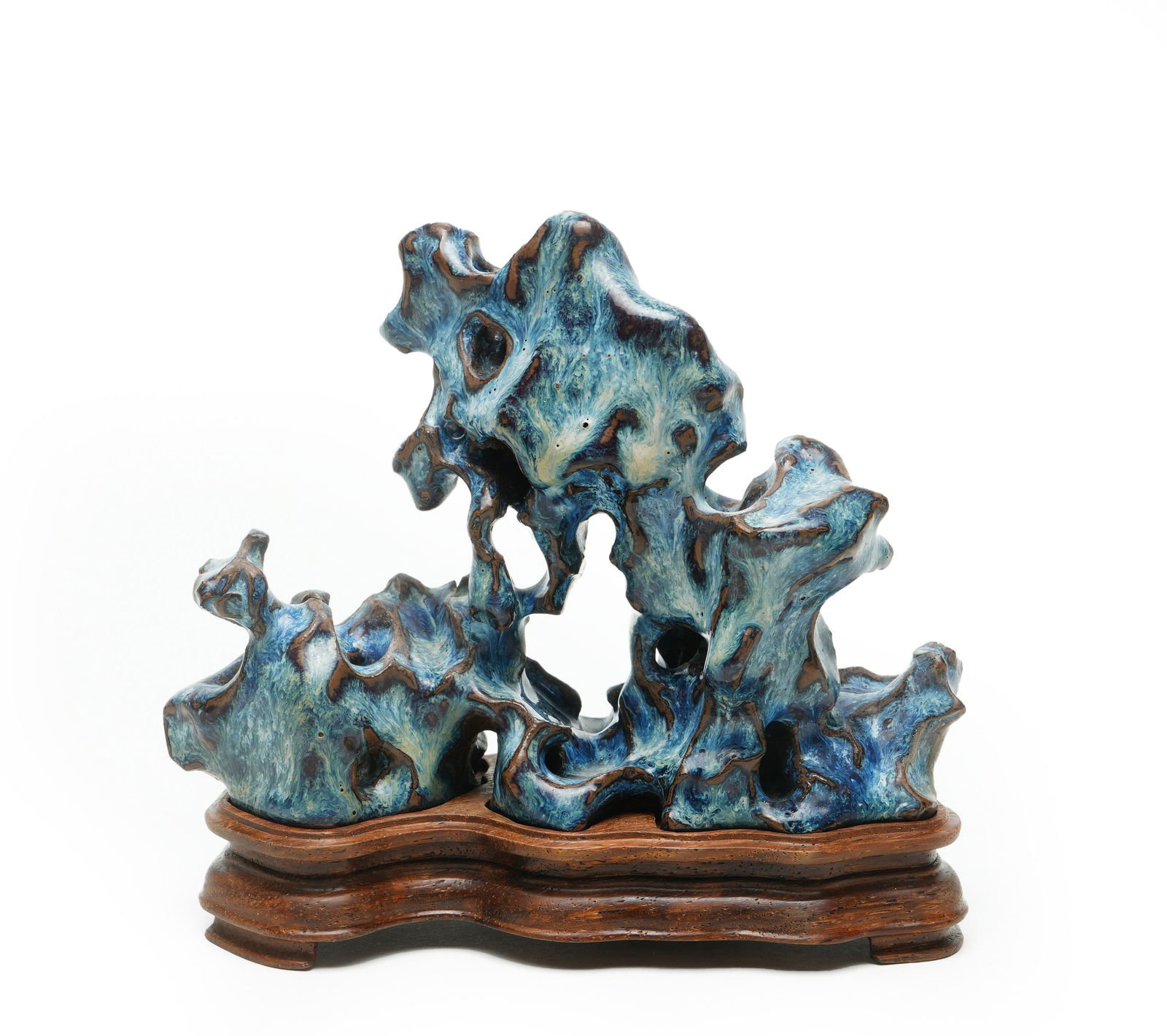 Qing Dynasty Flambe-Glazed Porcelain Ornament Imitating Taihu Stone: H:13cmW:14.5cm This is a Qing Dynasty flambe-glazed porcelain ornament imitating Taihu stone, accompanied by its original red wood stand. The ornament is shaped from porcelain clay to replicate the "s