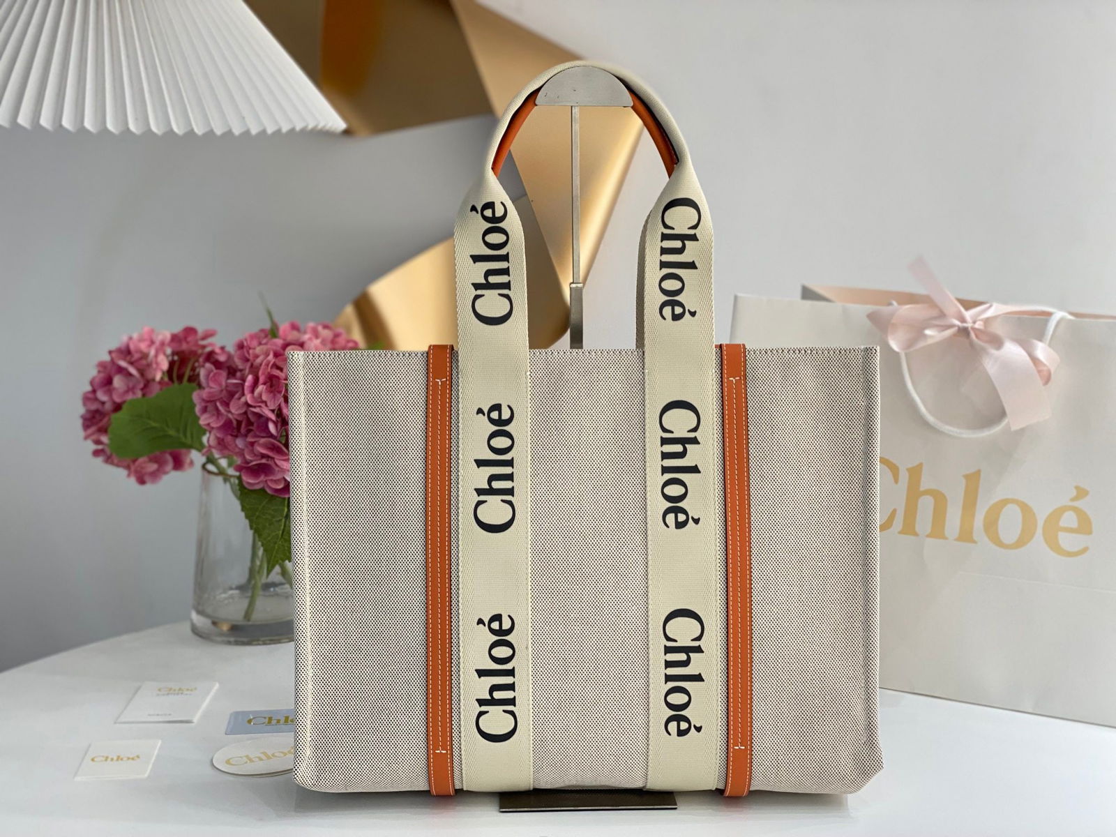 Chloe Woody Tote: The orange Chloe Woody Tote has been a hit with many women since its release. The bag is crafted from tightly woven waterproof cotton canvas. The black and white Chloe logo strap, which contrasts shar