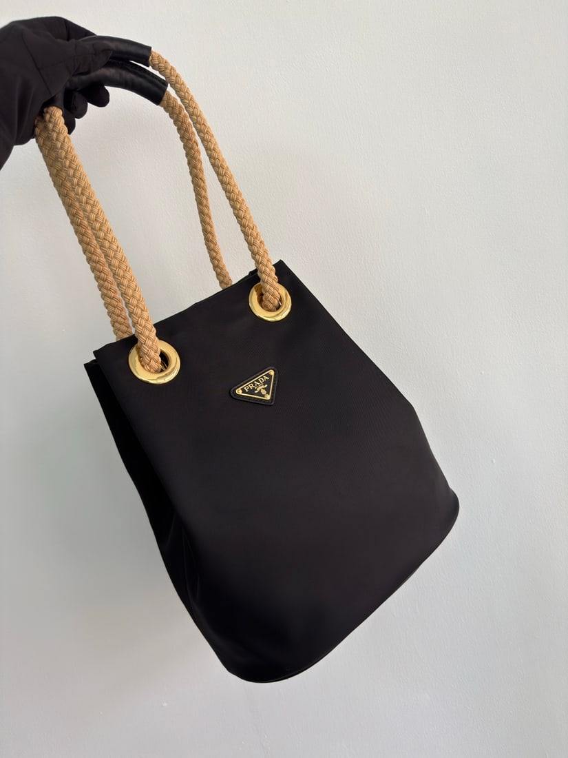 PRADA Re Nylon handbag: This Re Nylon handbag is designed with nylon fabric and calfskin. The unique combination adds a charming touch. The sliding rope handle highlights its versatility, allowing for easy hand carrying, sho
