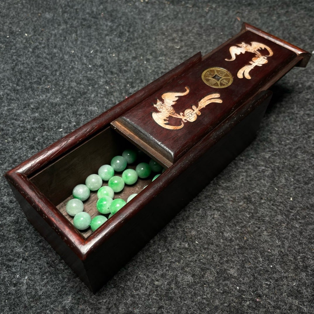 A precious jade clavicle necklace is housed in a rosewood box inlaid with mother-of-pearl. (1 of 9)