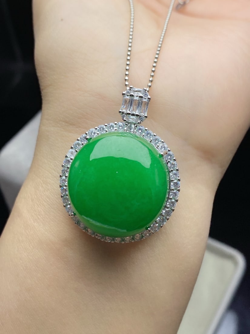 Jadeite of glutinous type with a bright green hue, set in an oval shape. (1 of 9)