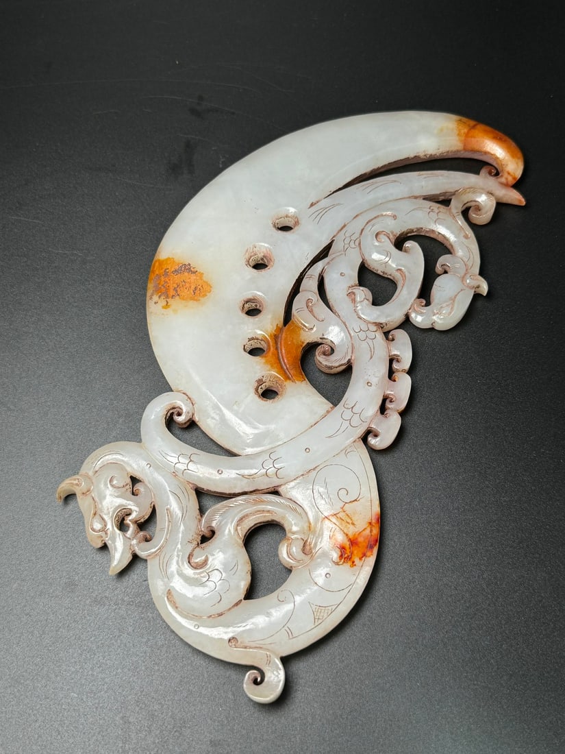 Hetian jade ancient jade weapons: This ancient Hetian jade weapon features a dragon and phoenix motif, symbolizing peace and protection. Its beautiful and imposing design, skillful carving, warm and lustrous jade quality, and excellen