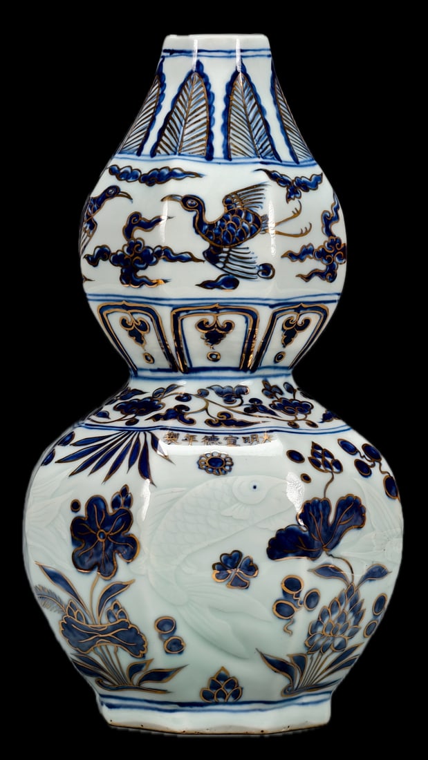 A blue-and-white gourd-shaped vase with a lotus pond and fish design, made during the Xuande period: The gourd-shaped vase in the picture is exquisitely crafted. Its entire body is covered in a white glaze, with incised fish and algae patterns, and underglaze blue depicting lotus flowers/auspicious c