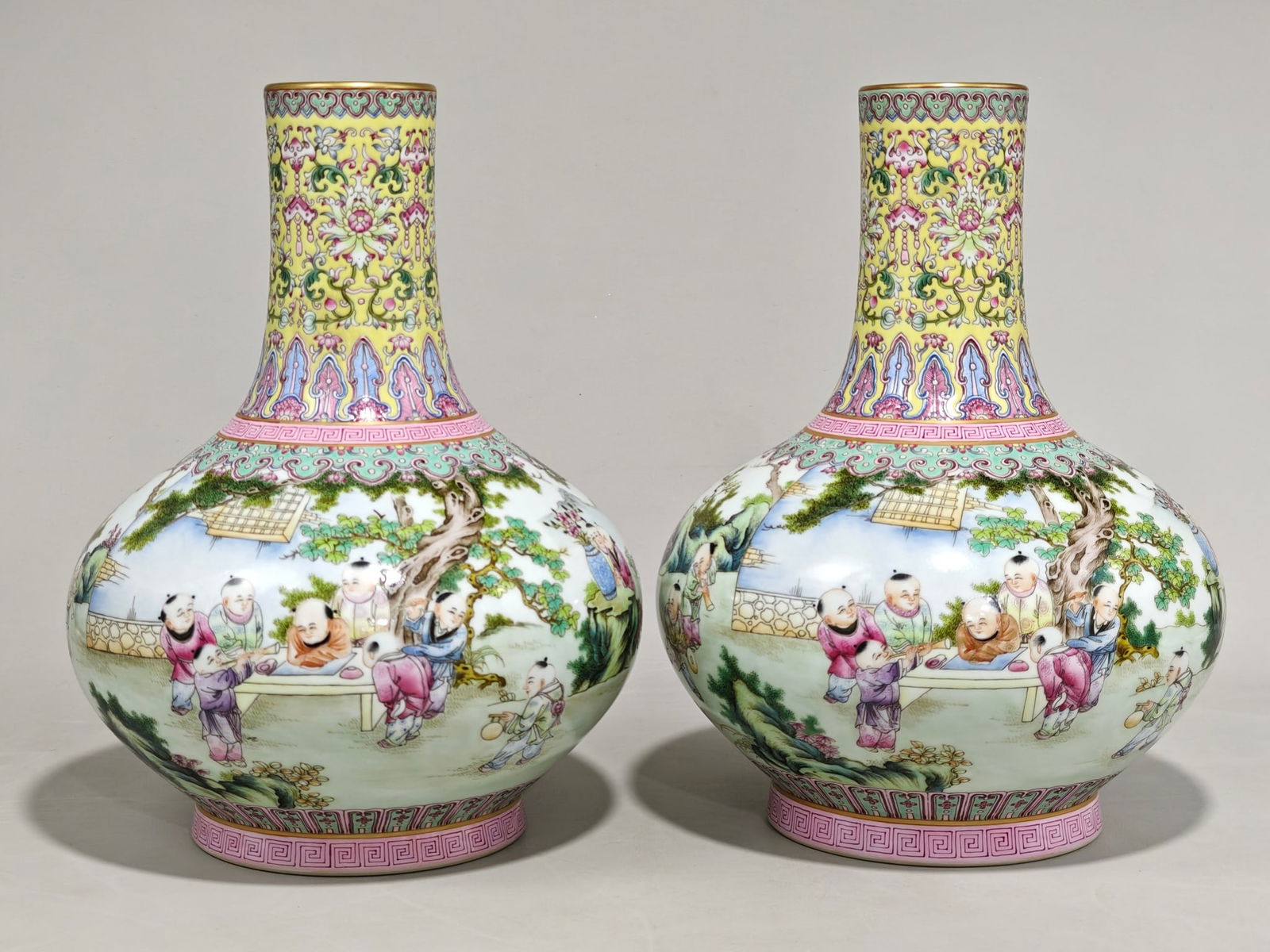A flat-bellied vase with a pale yellow base, lotus scroll design, and children at play, bearing the: A flat-bellied vase with a pinkish-yellow base, decorated with a lotus scroll pattern and a children's play scene, bearing the mark of the Qianlong period of the Qing Dynasty. It measures 28 cm in hei