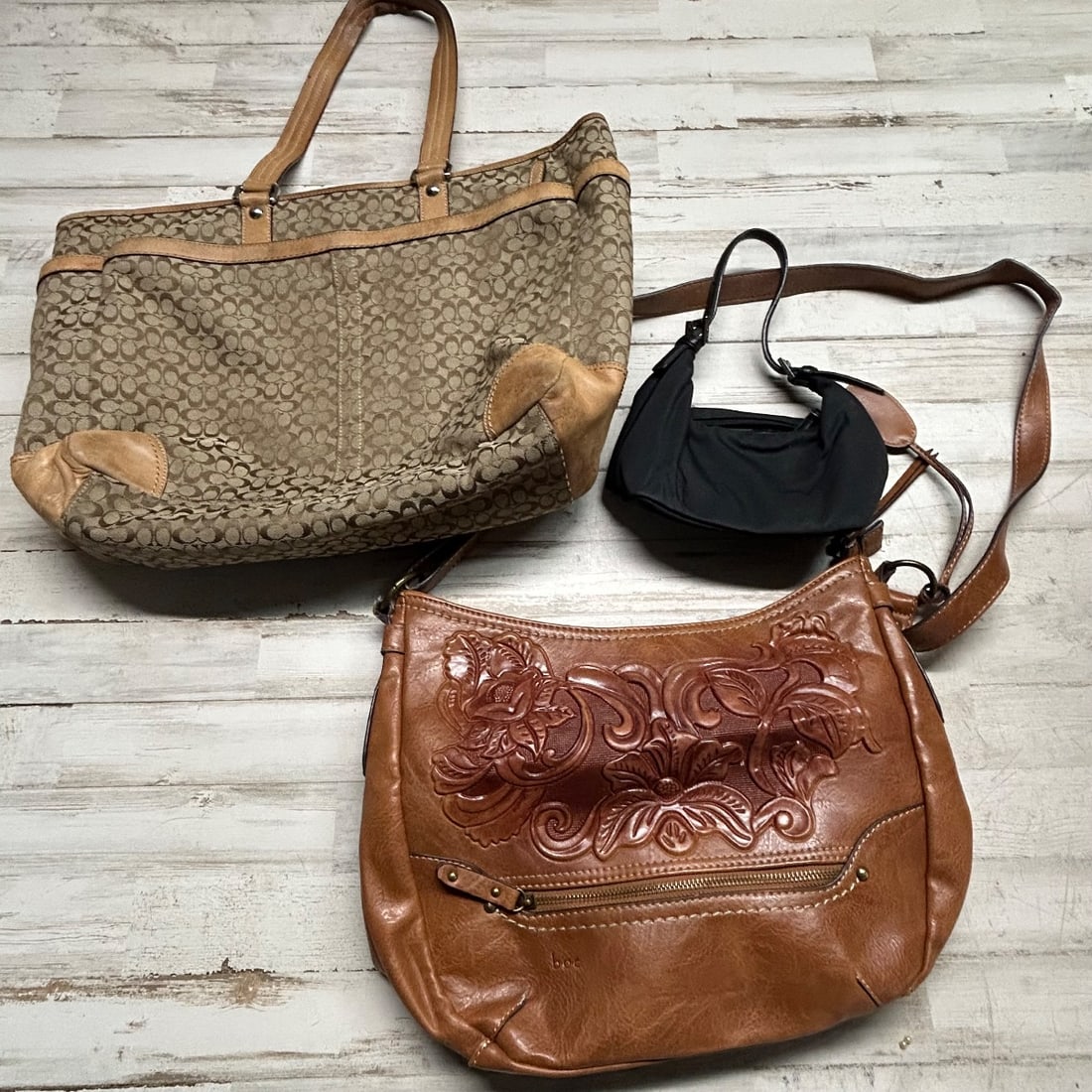 Coach Signature Canvas Tote, BOC Brown Embossed Leather Hobo, Small Black Purse: A collection of three handbags including a large Coach signature canvas tote with leather trim and stripe detail, a BOC (Born Concepts) brown leather hobo bag with intricate floral embossing, and a sm