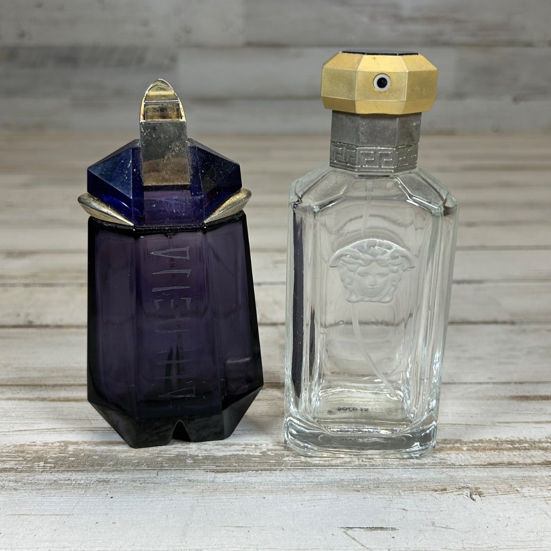 Thierry Mugler Alien & Versace The Dreamer Perfume Bottle Set Empty: This lot features two empty, collectible perfume bottles: Thierry Mugler's iconic Alien and Versace's The Dreamer. The Alien bottle is crafted from deep purple glass with a geometric, faceted design a