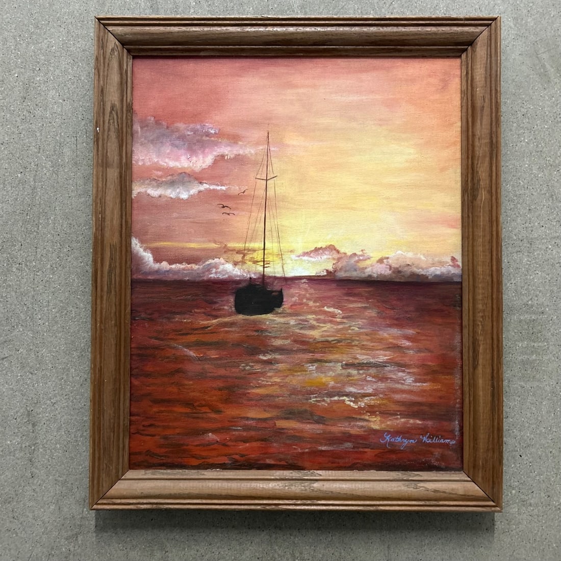 Original Kathryn Williams "Sunset Sail" Oil Painting Framed Seascape Art: This is an original oil painting by artist Kathryn Williams, titled "Sunset Sail." The artwork depicts a lone sailboat at sea during a vibrant sunset, with dramatic clouds reflecting in the shimmering