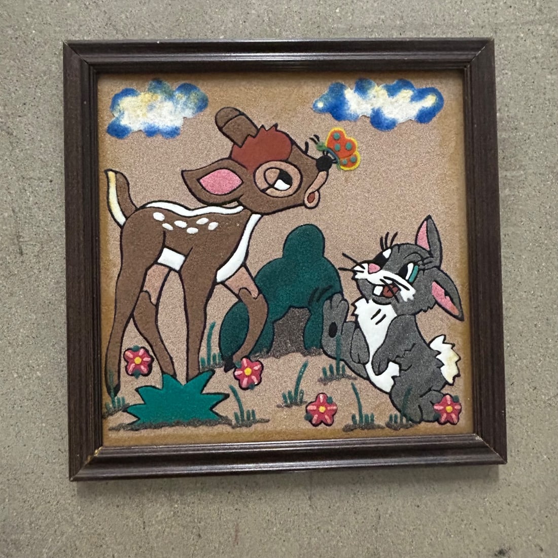 Vintage Bambi & Thumper "Sand Art" Framed Picture 2002: Charming framed "sand art" picture featuring Disney characters Bambi and Thumper interacting with a butterfly. The artwork is created using colored sand adhered to a textured background, framed in a d
