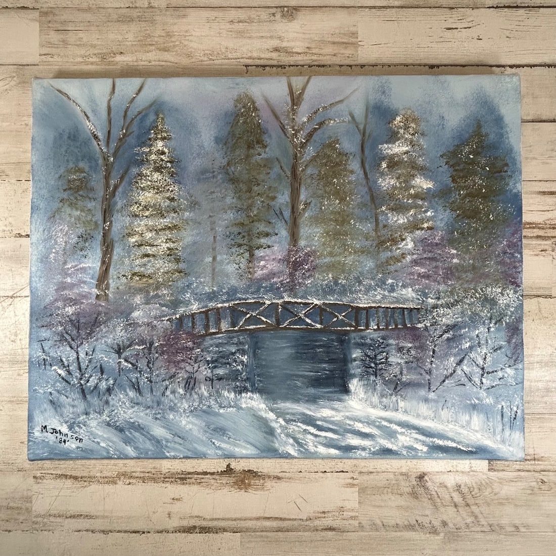 M. Johnson "'84" Original Winter Landscape Painting Bridge Snow Scene: Original acrylic painting depicting a serene winter landscape with a snow-covered bridge spanning a dark blue stream. The scene features snow-laden evergreen trees, bare deciduous trees, and delicate