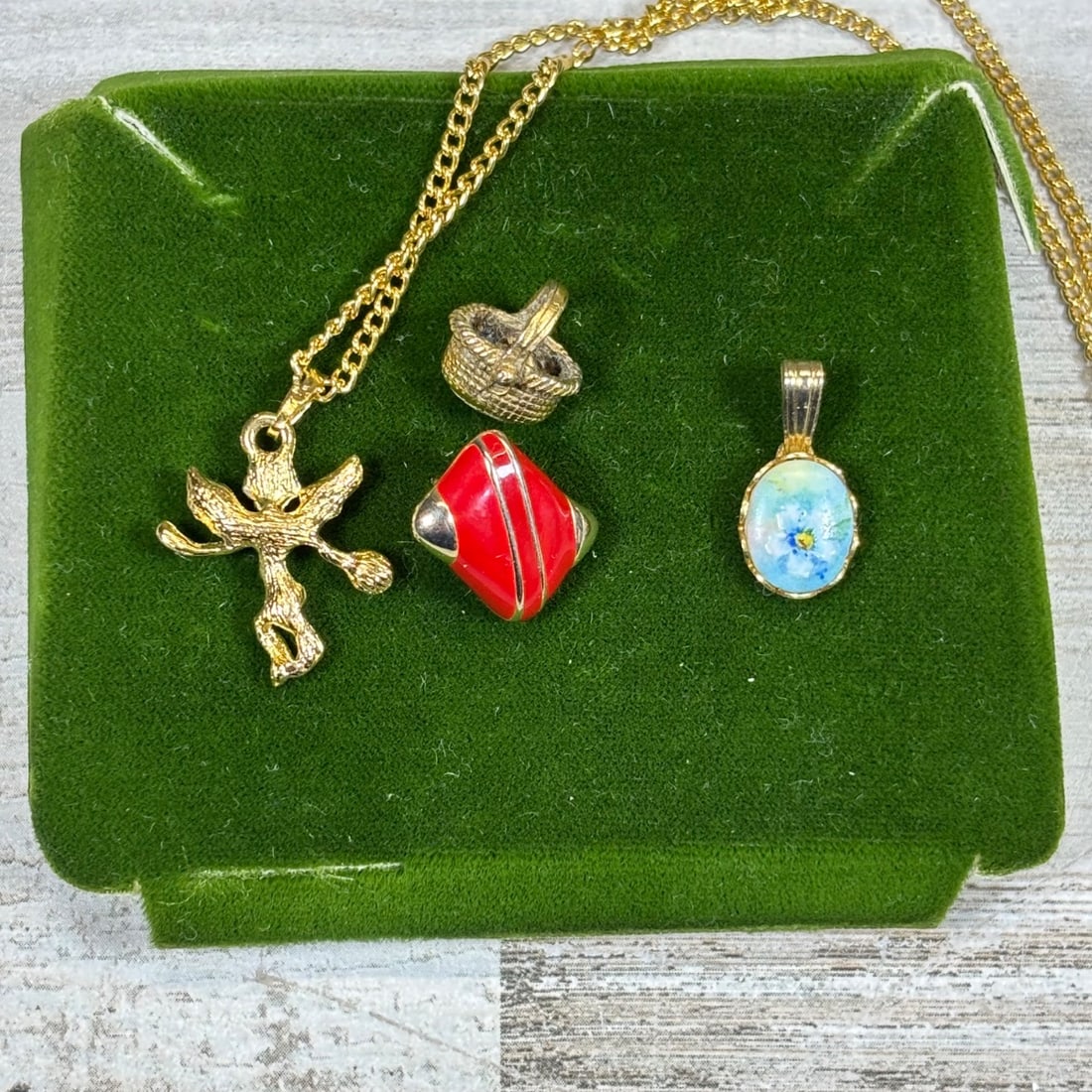 Lot of 4 Vintage Charms & Pendant: Gold Tone Flying Figure, Red Enamel, Basket, Blue Floral: This lot features a charming collection of four vintage jewelry pieces, including a gold-tone chain with a unique flying figure pendant, a small woven basket charm, a striking red and silver tone enam