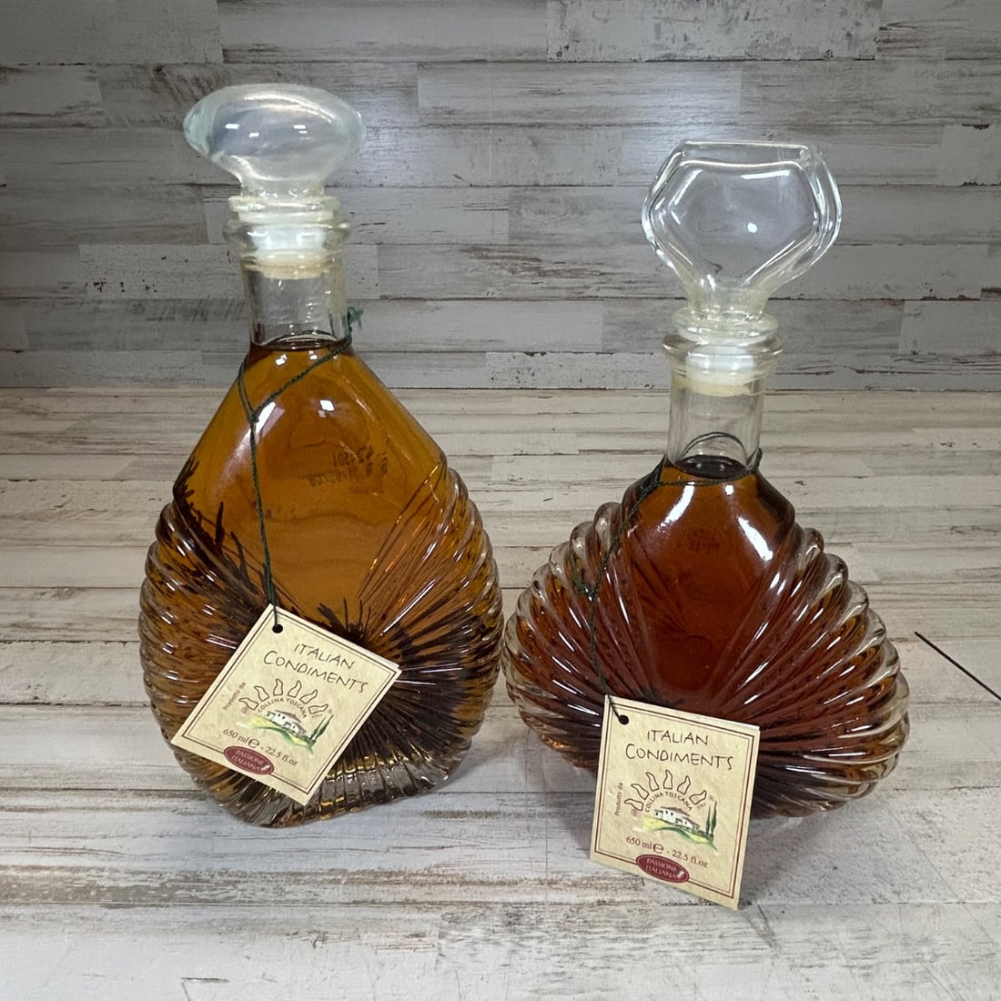 Vintage Italian Glass Decanters with Stopper, Set of 2, Amber Resin: A charming set of two vintage glass decanters, originating from Italy. These decorative bottles are filled with what appears to be amber-colored resin or oil, and are topped with clear glass stoppers.
