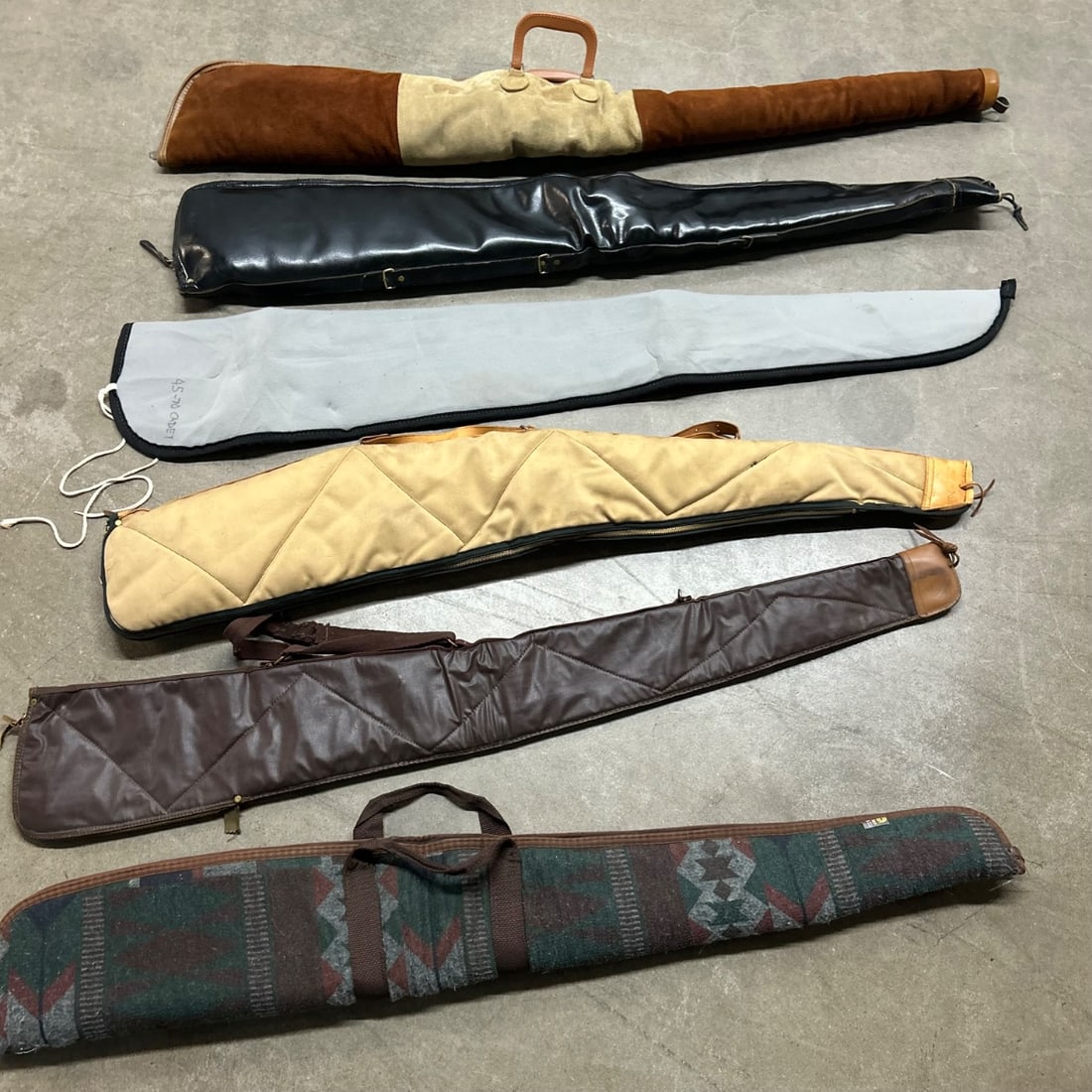 Lot of 6 Vintage Gun Cases - Assorted Materials & Styles: This lot features six assorted vintage gun cases, offering a variety of styles and materials. These cases range from traditional leather and suede to quilted canvas and patterned fabrics, likely datin