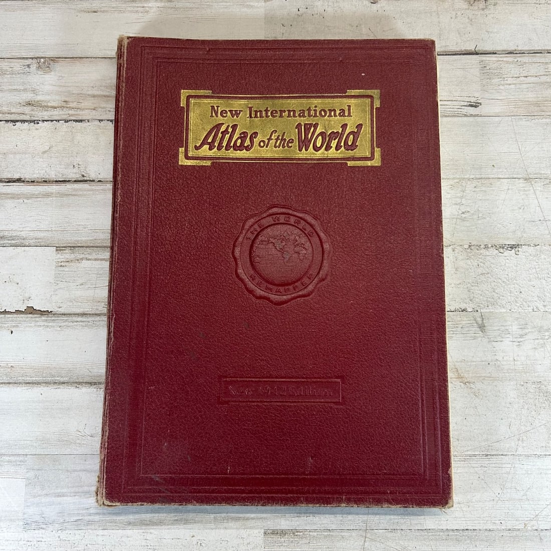 Vintage New International Atlas of the World 1942 Edition Hardcover Book: This is a vintage hardcover edition of the New International Atlas of the World, published in 1942. It features comprehensive maps and geographical information from that era. The cover is a deep red w