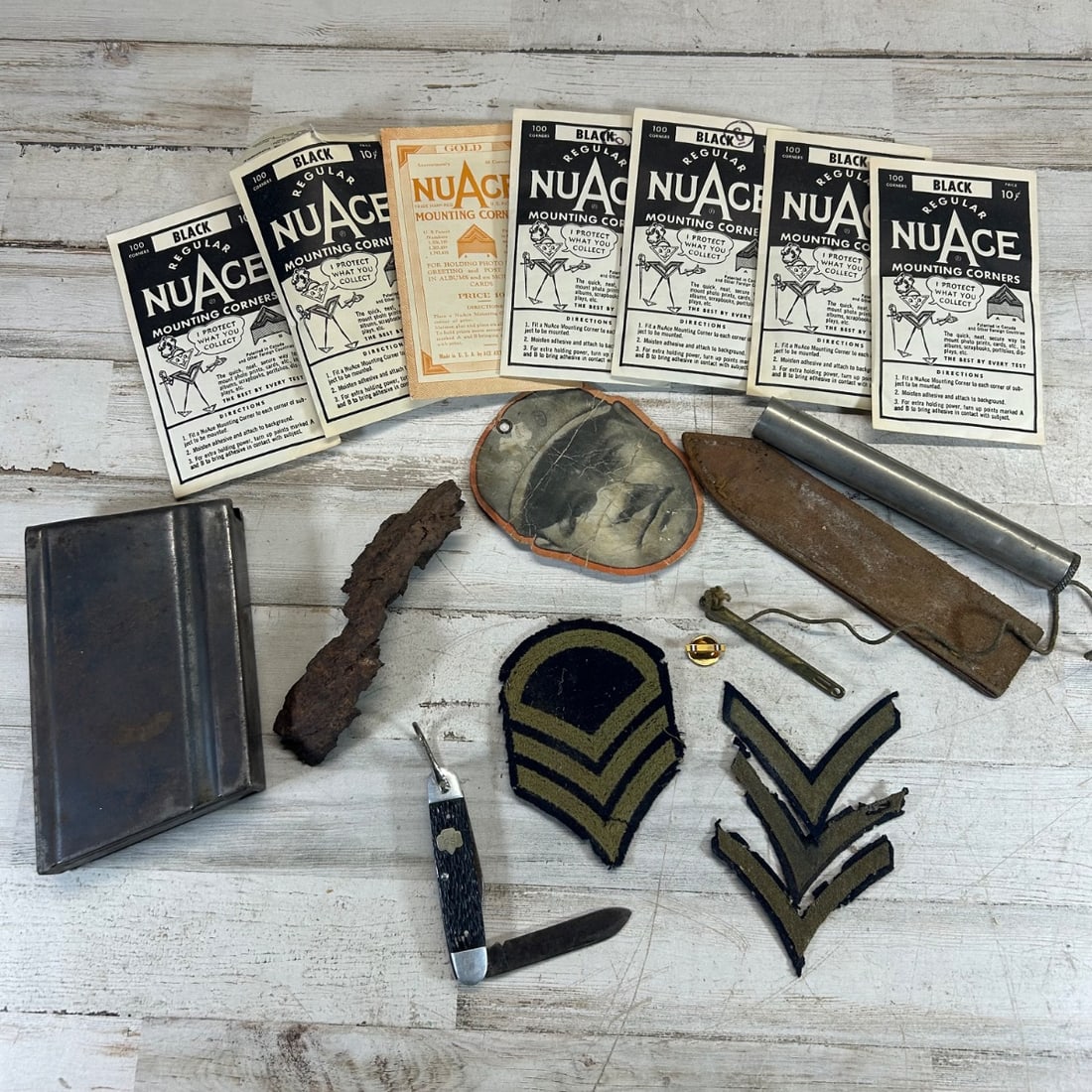 WWII Era Collectibles Lot: Knife, Rank Insignia, Magazine, Relics, Photo Holder: This lot features a collection of World War II era items, offering a glimpse into the past. Included is a folding pocket knife with dark checkered handles and a "GS" initial mark, along with an assort