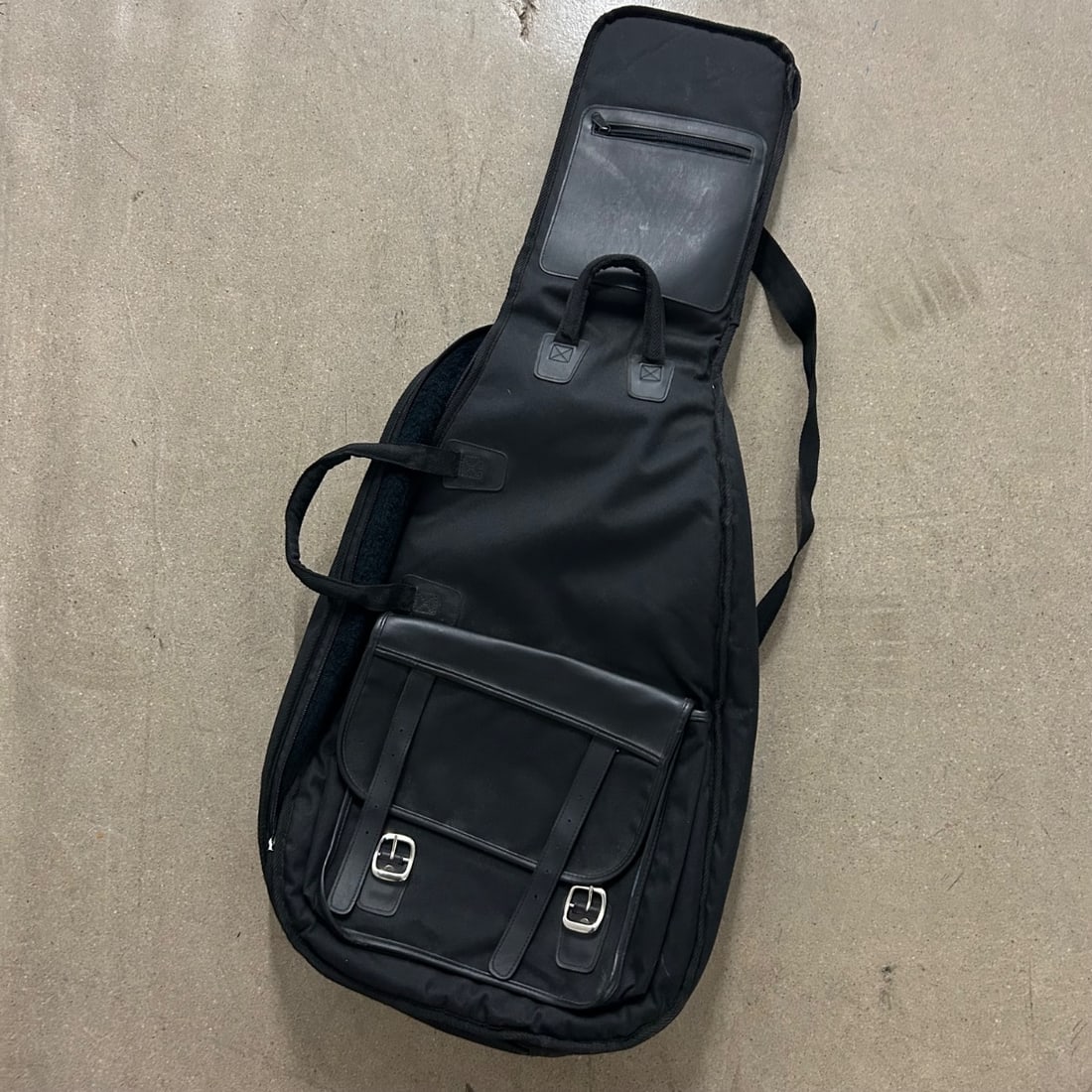 Black Padded Guitar Gig Bag Case w/ Front Pockets & Straps: This is a black padded gig bag designed for electric or acoustic guitars. The exterior is made of durable nylon fabric with faux leather accents on the buckles and straps of the large front storage po