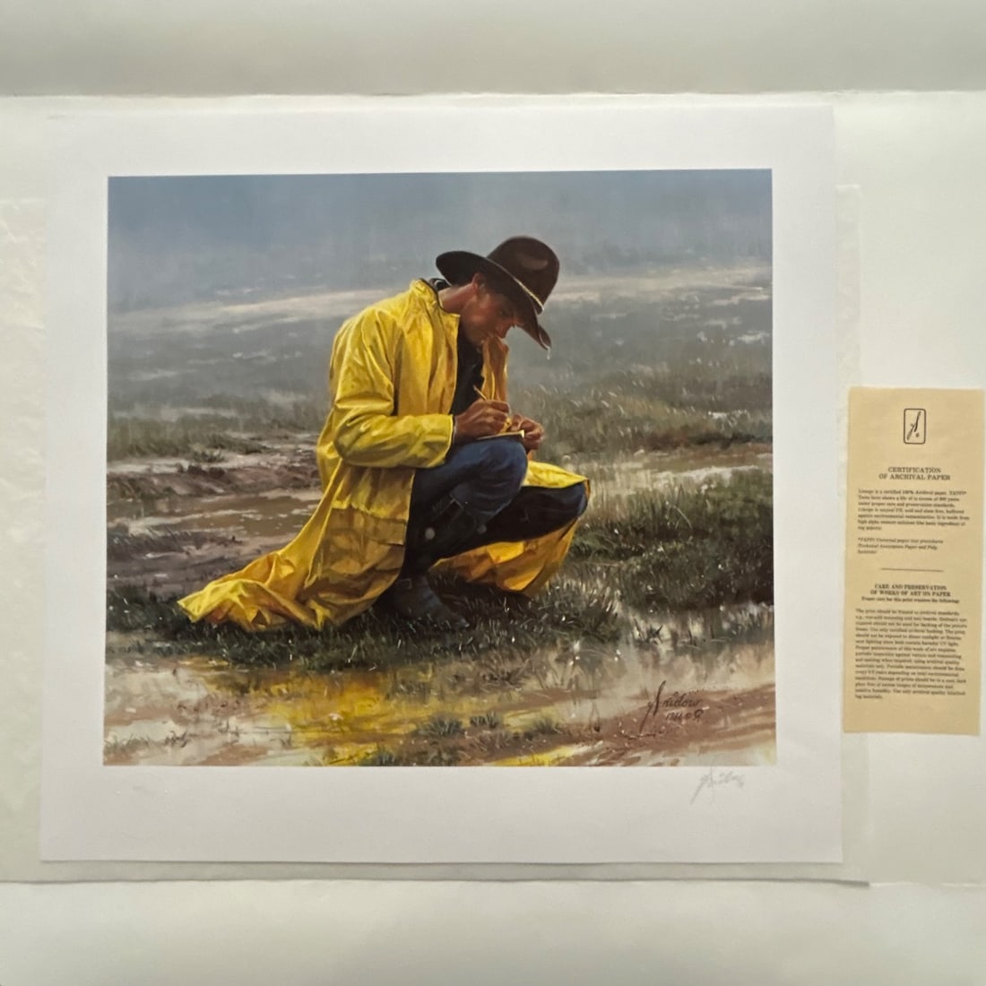 Western Art Print "Out of the Rain" by D. Snidow, 1986, Signed, Numbered 48/900: This is a limited edition print titled "Out of the Rain" by renowned Western artist D. Snidow, created in 1986. The print depicts a cowboy in a yellow raincoat squatting in a muddy field, diligently t