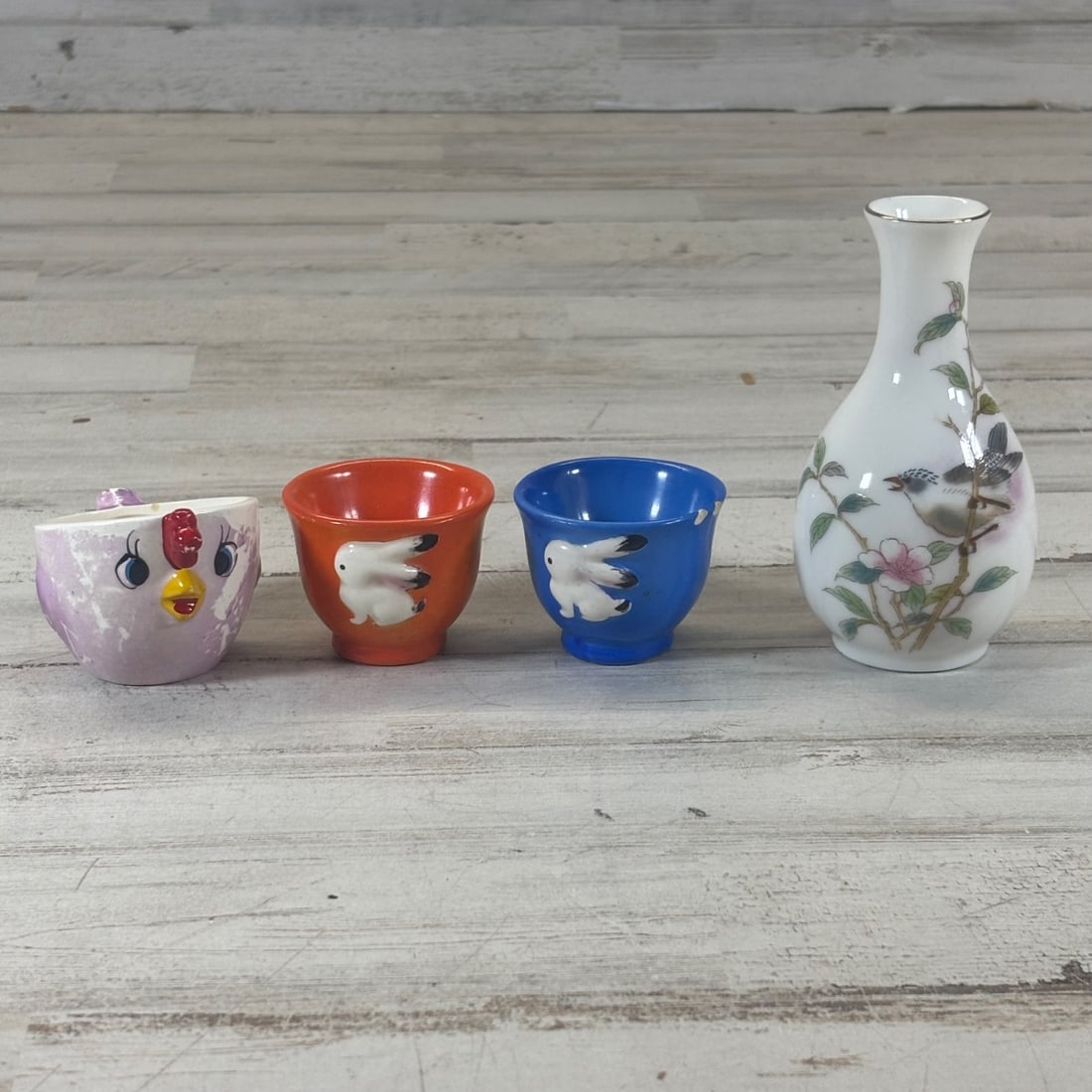 Japanese Porcelain Vase & (3) Ceramic Cups - Birds, Flowers, Bunny Motif: This charming lot features a Japanese porcelain vase adorned with delicate birds and floral motifs, alongside three ceramic cups. The vase has a slender neck with a thin gold rim and a distinctive ori