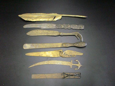 Set of 7 brass library knives: 1) feather shaped: Set of 7 brass library knives: 1) feather shaped pen, 2) anchor with carving on knife end, 3) snail crawling, 4) birds and bugs, 5) claw with feather end, 6) bird scene and 7) knife with bird handle,
