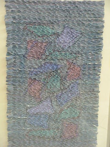 Handwoven paper design inside a clear shadow box