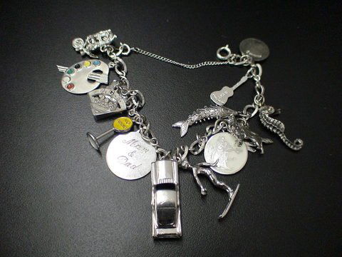 Silver charm bracelet with many charms: a paint p: Silver charm bracelet with many charms: a paint palette, Aries Zodiac sign, a car, a woman skiing, a guitar, a seahorse, a fish, pair of scissors, a dog, etc.