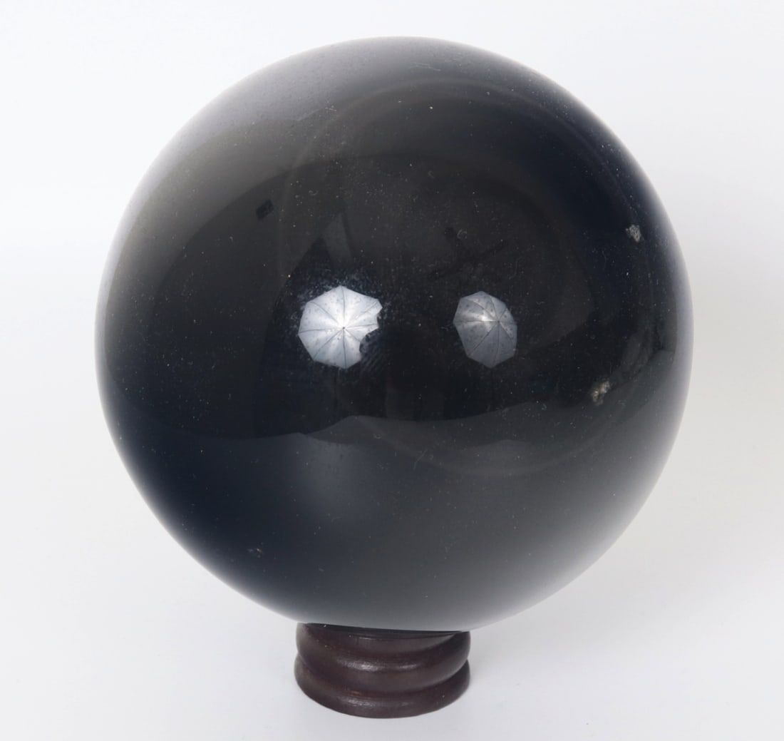Large Polished Obsidian Sphere with Stand: Finely polished obsidian mineral specimen in the shape of a sphere with a custom wood base for easy display on a desk or mantle. Unique eye shape hidden in the sphere as shown. Soft and smooth to the