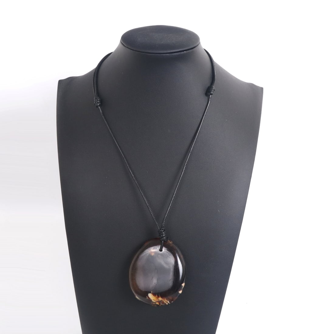 Beautiful Amber Style Necklace: Polished circular amber style pendant with beautiful warm caramel colors throughout with crystal like inclusions. Suspended on an adjustable cord to be worn long or short. Size of pendant 2 1/2" H