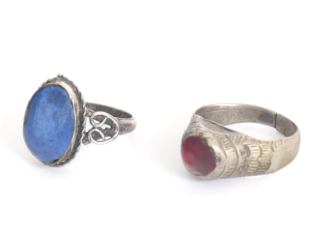 Group of Two Early Persian Rings: Persian silvered rings, one with a lovely carnelian style gemstone and the other with a lovely cut and polished section of lapis lazuli. Both bands are intricately detailed with incised and high