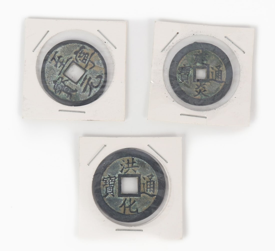 Group of Three Early Chinese Style Coins: Three Chinese early style coins in cardboard and plastic cases. Each pierced through the center with a square whole in classic form. Size of case 1 3/4" W (4.4cm W) Size 1 3/4" W (4.4cm W)