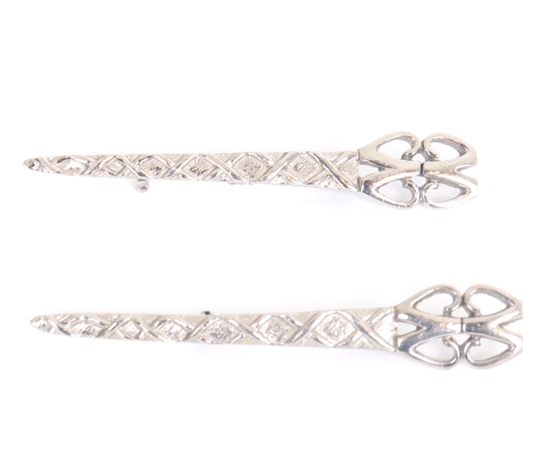 Vintage Pair of Revival Sword Brooches: Lovely pair of elongated silver tone brooches draws inspiration from Art Deco elegance and medieval revival forms, resembling stylized swords or dress clips with ornate geometric and openwork handles.