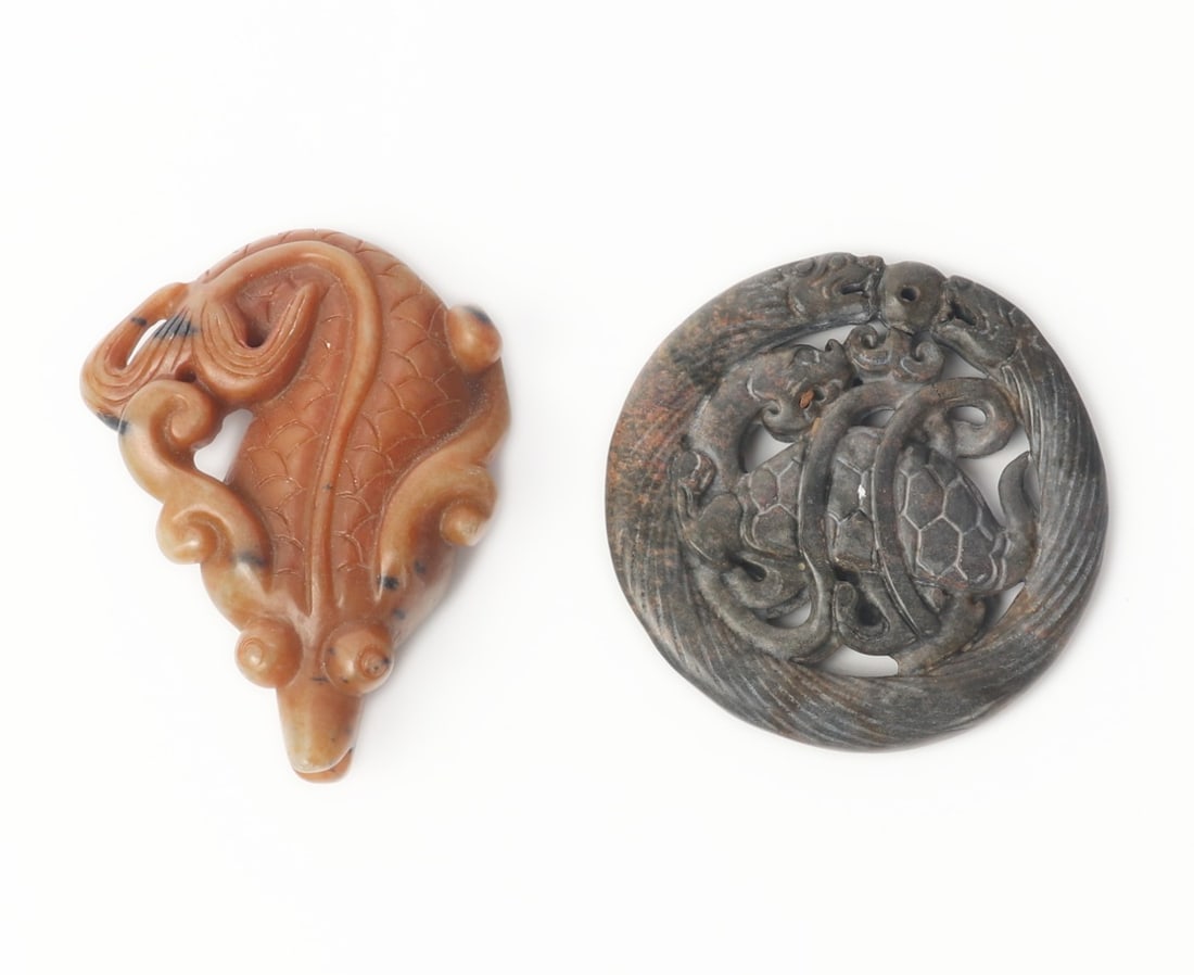 Two Chinese Jade Style Carvings: Two Chinese jade style carvings, one in a orange jade style stone in a zoomorphic figure form. Other piece carved from a black jade style stone depicting two dragons at the top and a turtle dragon to