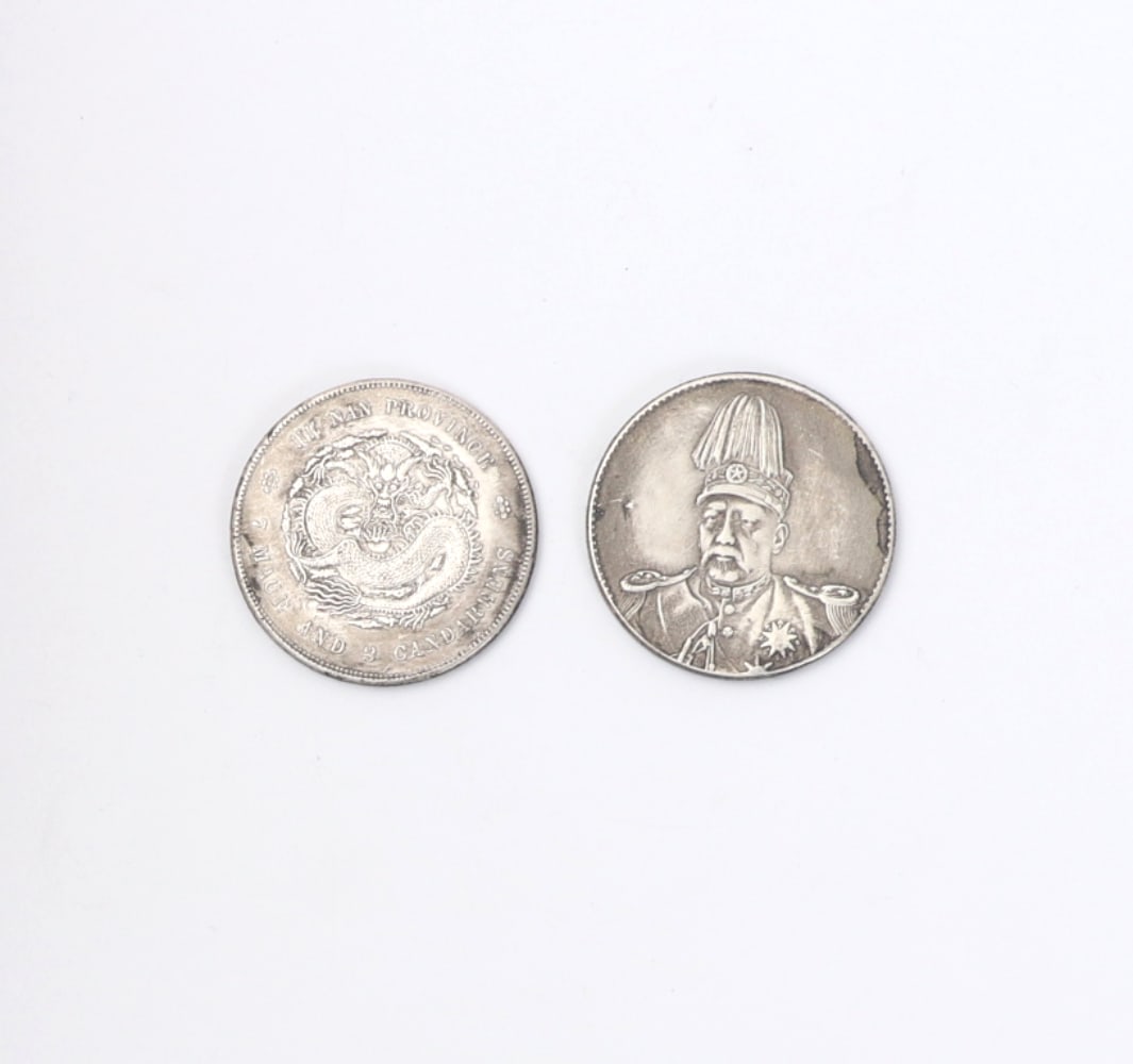 Two Chinese Silver Style Coins: Two Chinese silver style coins, each depicting ferocious dragons in fine detail. One dragon holds arrows in his talons and the other dragon is hovering protectively above a flaming pearl. Size of