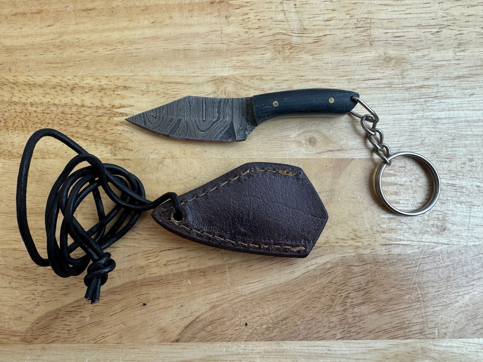 Beautiful Handmade Damascus Steel KeyChain Knife w/Sheath: Beautiful Handmade Damascus Steel Necklace/KeyChain Knife w/Sheath. See photos for details and measurements. Meticulously crafted by skilled artisans, each knife is forged from multiple layers of high