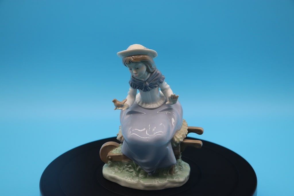 LLADRO FIGURE: AN NAO BY LLADRO FIGURE OF A GIRL HOLDING A BIRD ON A WHEEL BARROW. VERY GOOD CONDITION. 6.5"