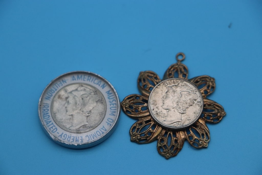 MERCURY DIMES: A PAIR OF SILVER MERCURY DIMES. ONE IS IN A CHARM AND THE OTHER IS IN A HOLDER FROM THE ATOMIC ENERGY MUSEUM.