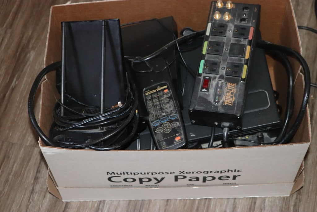 ELECTRONICS: A BOX OF ELECTRONICS WITH CORDS, POWER STRIPS AND MORE.