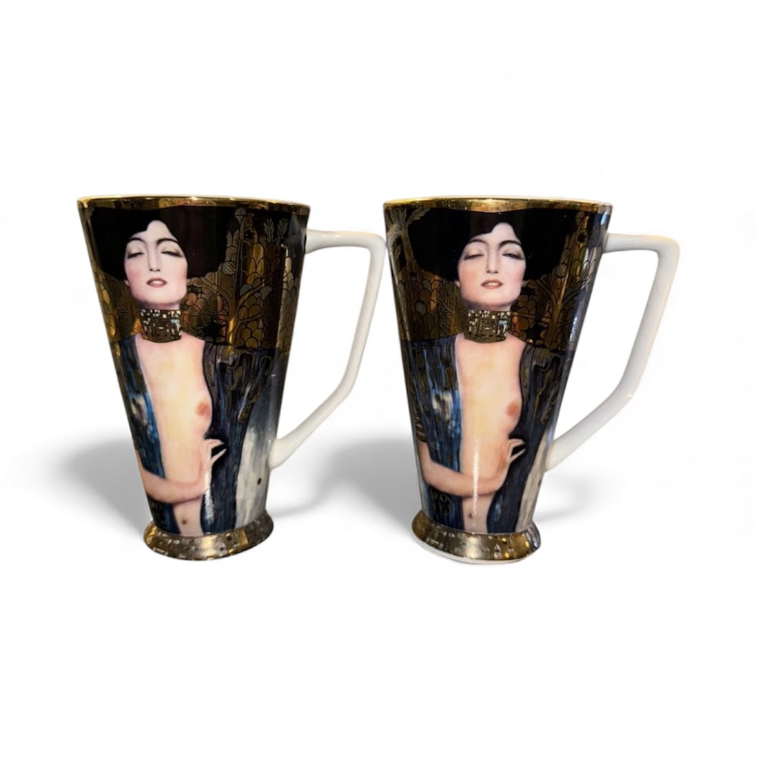 Goebel Artis Orbis - Gustav Klimt “Judith 1” Cups/ Mugs, Set of 2: The Goebel Artis Orbis mug/ cup features artwork by Gustav Klimt, specifically his piece "Judith 1." The mug stands at 6 inches tall and is made of porcelain in Germany. The design showcases a multico