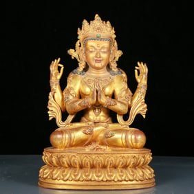 A solemn gilt bronze statue of Guanyin with four arms inlaid with precious stones