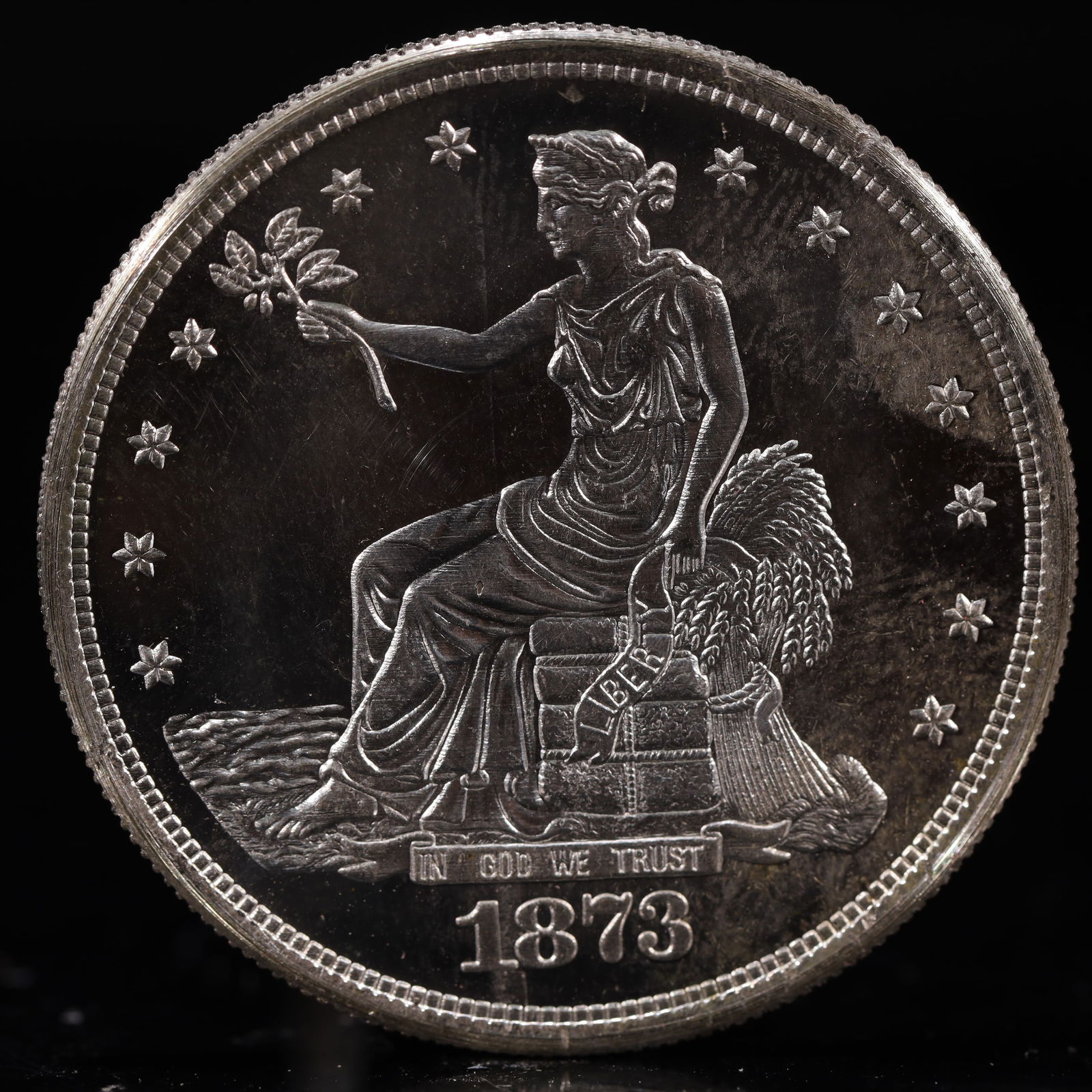 USA Trade Dollar 1873 Coin: American coin. Obverse: Liberty seated on a pedestal facing the sea to the left holding olive branches surrounded by 13 stars. IN GOD WE TRUST / LIBERTY / 1873. Reverse: An eagle holding branches