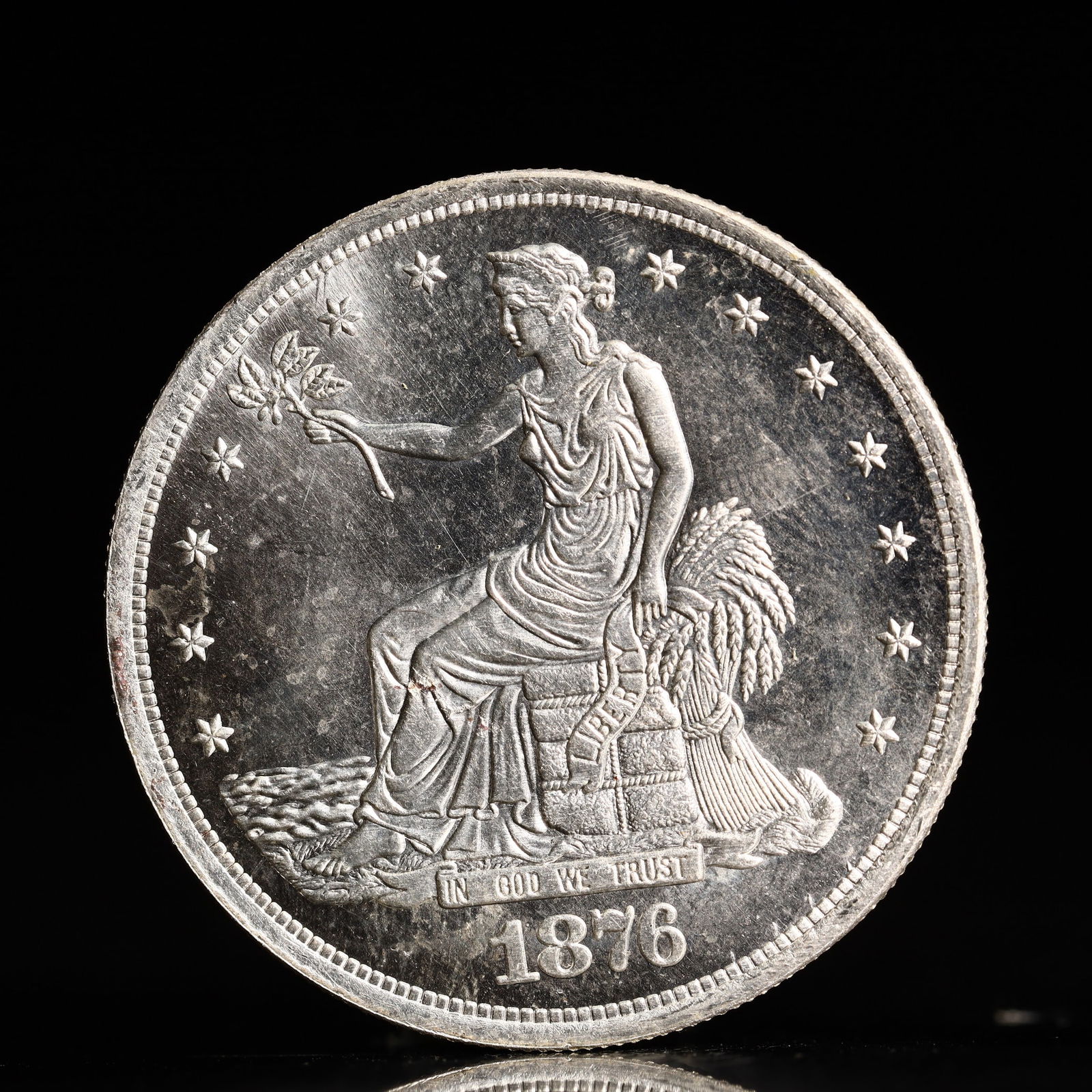 USA Trade Dollar 1876 Coin: American coin. Obverse: Liberty seated on a pedestal facing the sea to the left holding olive branches surrounded by 13 stars. IN GOD WE TRUST / LIBERTY / 1876. Reverse: An eagle holding branches