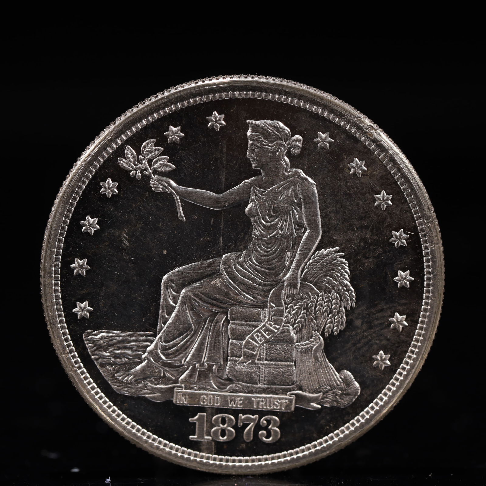 USA Trade Dollar 1873 Coin: American coin. Obverse: Liberty seated on a pedestal facing the sea to the left holding olive branches surrounded by 13 stars. IN GOD WE TRUST / LIBERTY / 1873. Reverse: An eagle holding branches with