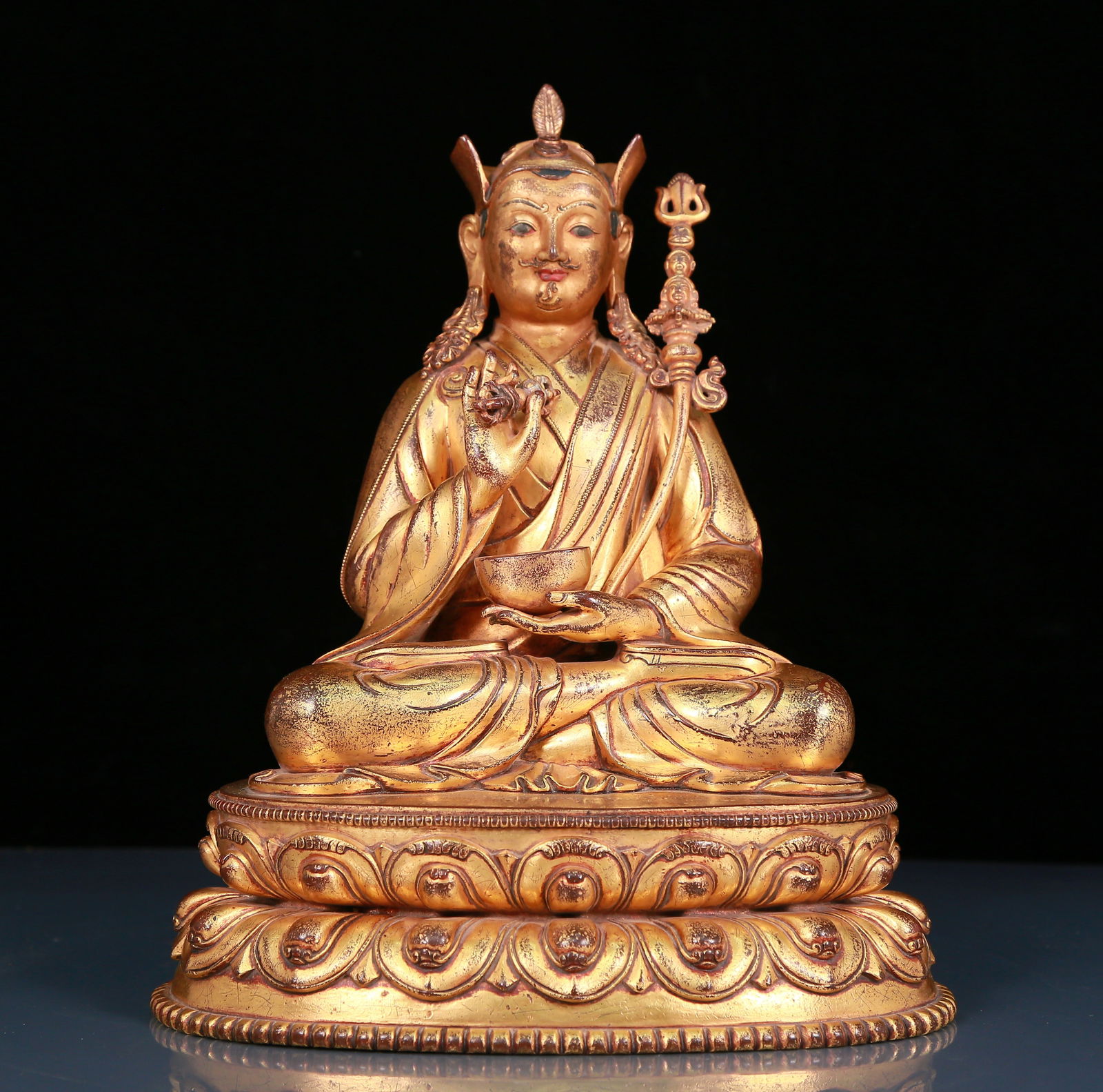 A Magnificent Gilt-Bronze Figure Of Padmasambhava: Magnificent Gilt-Bronze Figure Of Padmasambhava. Seated with a dignified expression, body rendered clad in long, flowing robes, the voluminous drapery elegantly cascading in folds, one hand holding a