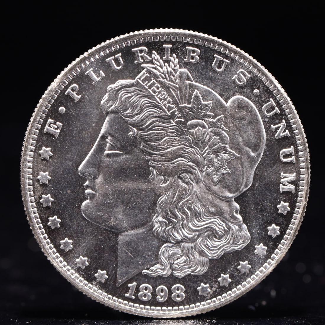 USA Morgan Dollar 1898 Coin: Obv: profile bust with date below and E PLURIBUS UNUM legend and stars around. Rev: eagle with In God we trust above within wreath with UNITED STATES OF AMERICA ONE DOLLAR legend. IN GOD WE TRUST / LI